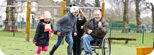 disabled man in wheelchair with his family playing in a park