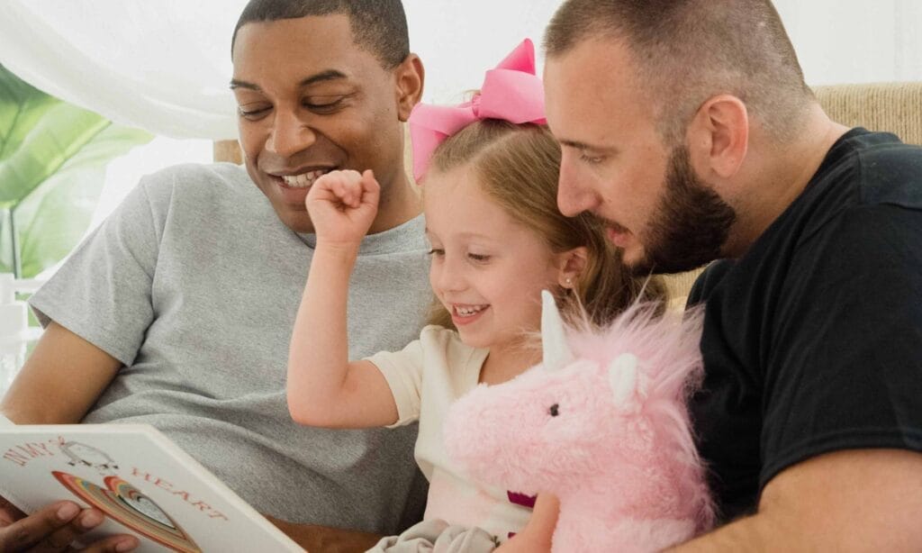 Two dads reading with their daughter