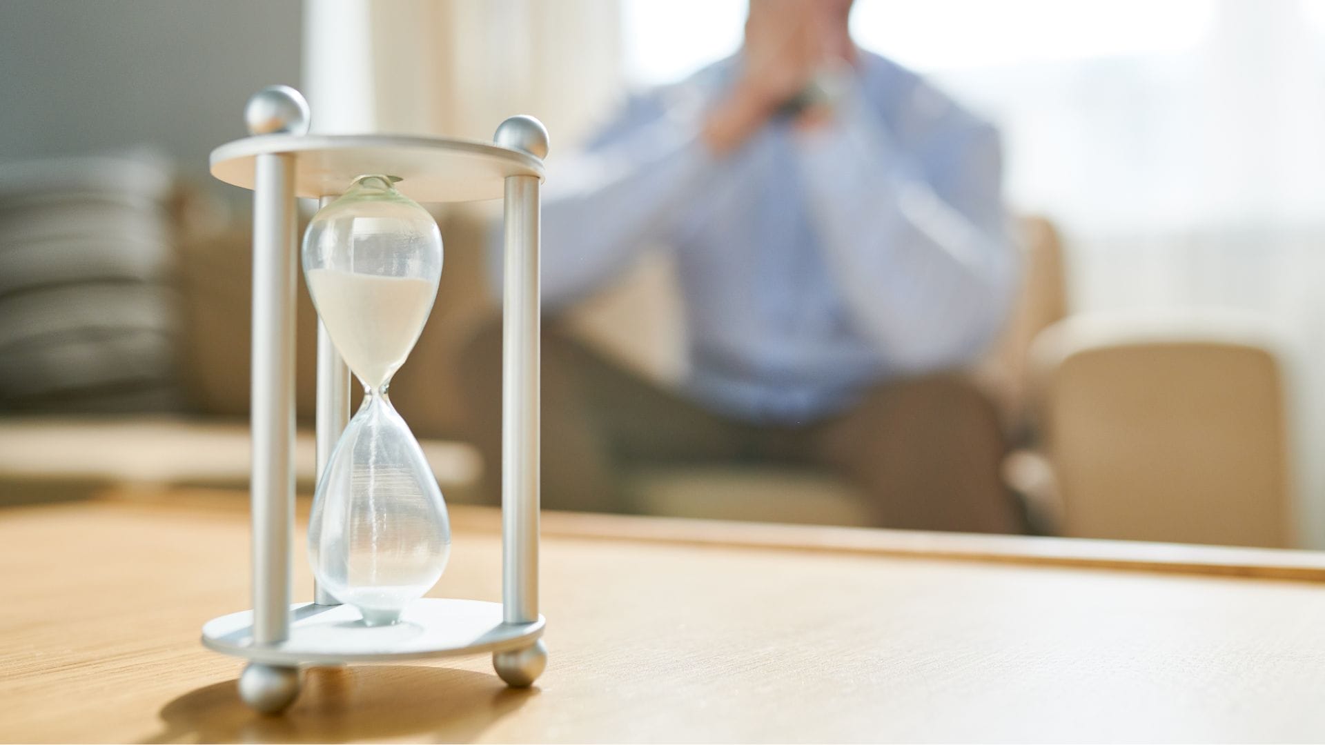 A man sat on the sofa watching a sand timer