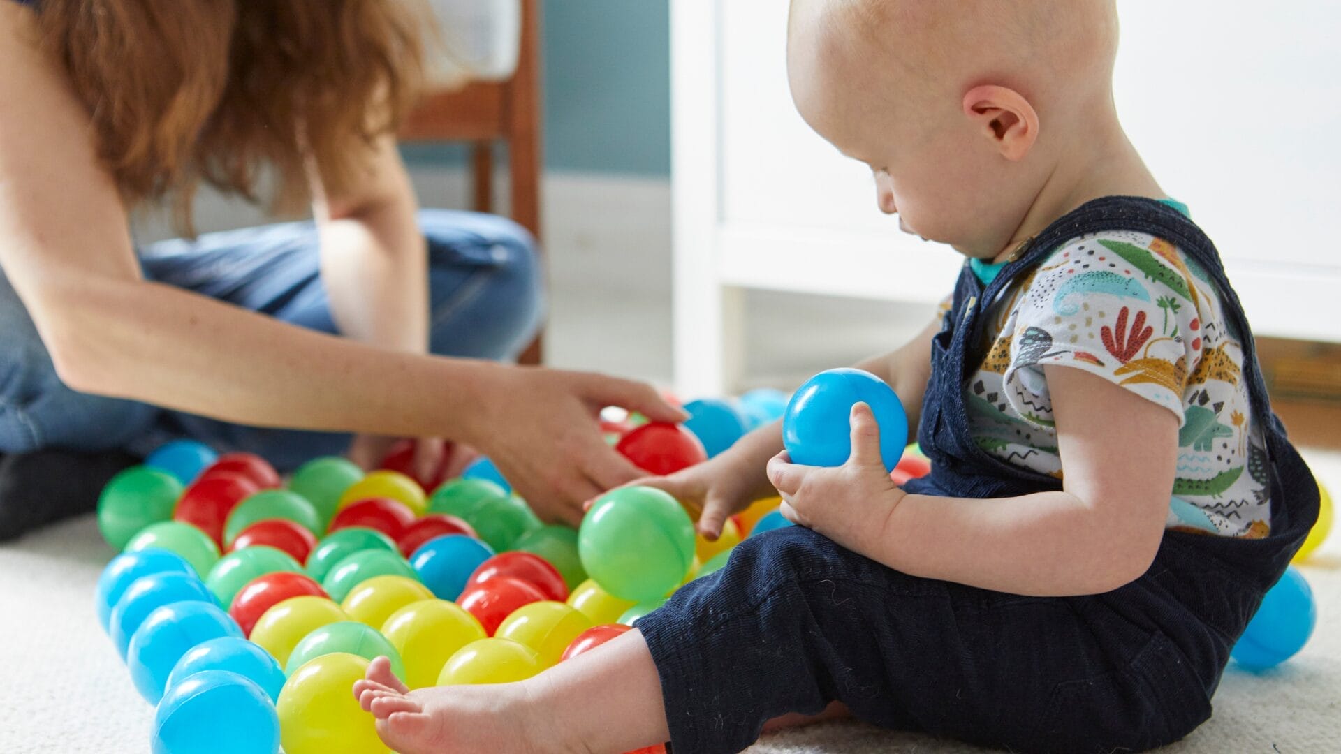 Baby and mum sat playing with colourful balls | CATCH Baby and mum sat playing with colourful balls